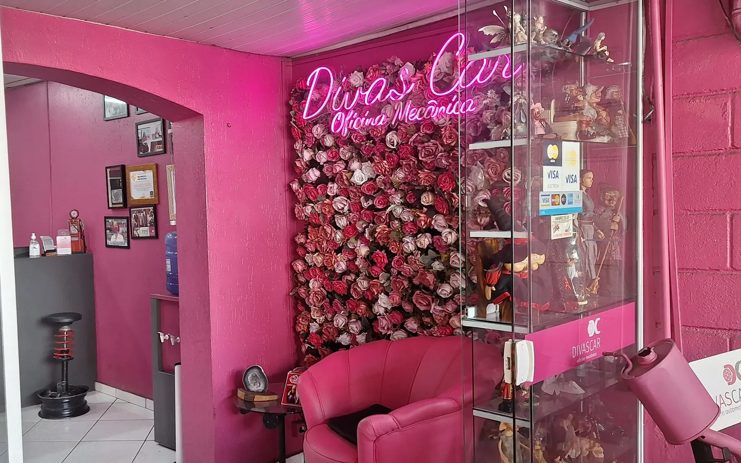 Entrada com parede de flores, neon Divas Car e poltrona rosa